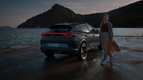 woman standing next to the new cupra formentor suv with full led lights